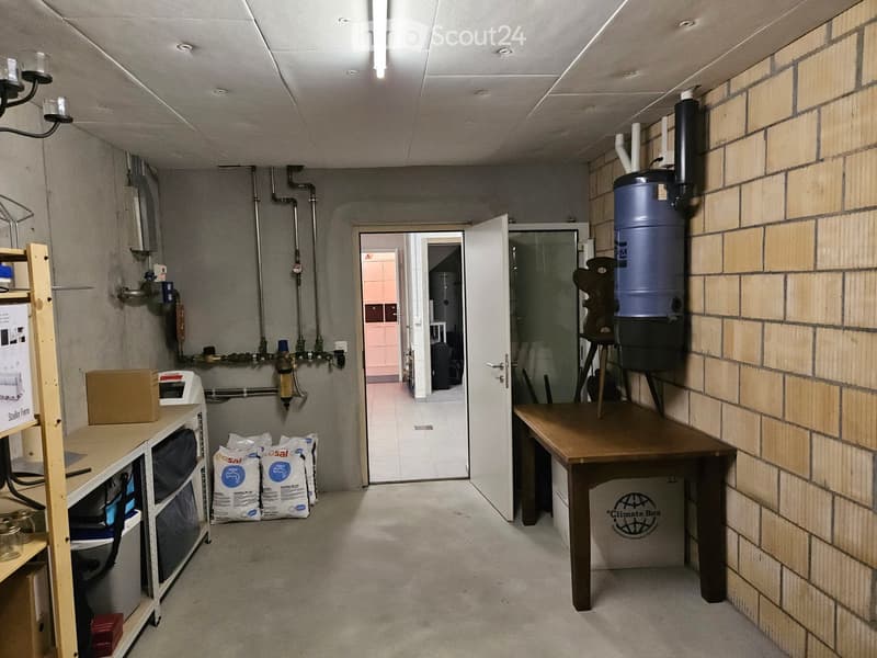 Storage room with shelves, table, open door, pipes, and bags of salt