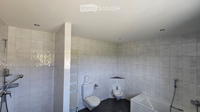 modern bathroom with white tiles, white toilet, bidet, bathtub, shower, towel rack