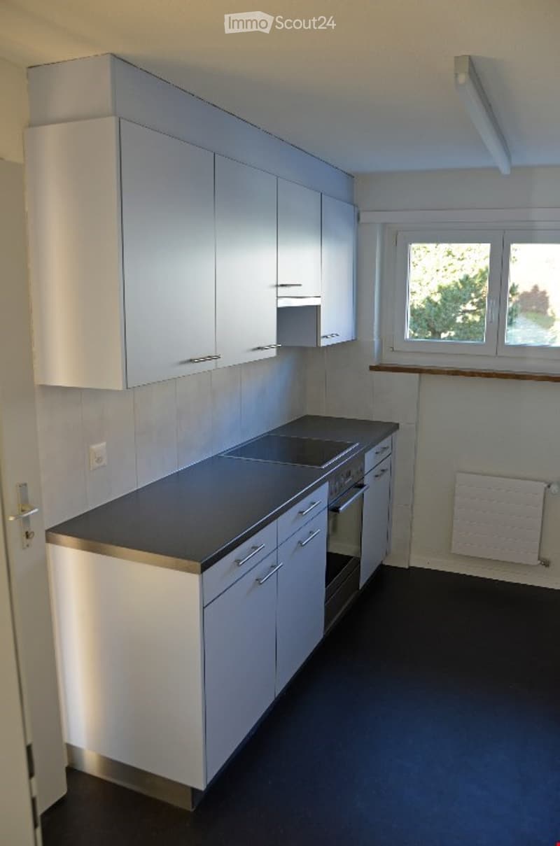 modern kitchen with white cabinets, black countertops, integrated oven, dishwasher, and washing machine