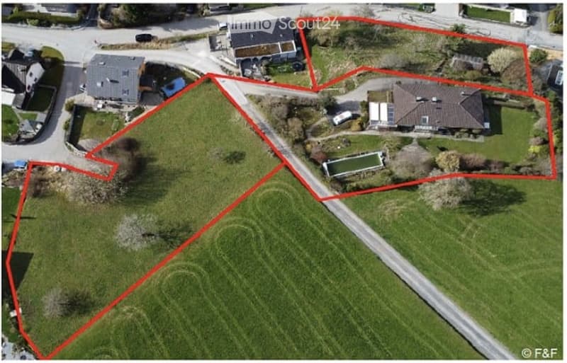 Aerial view of a property with three houses, a road, and a large green field.