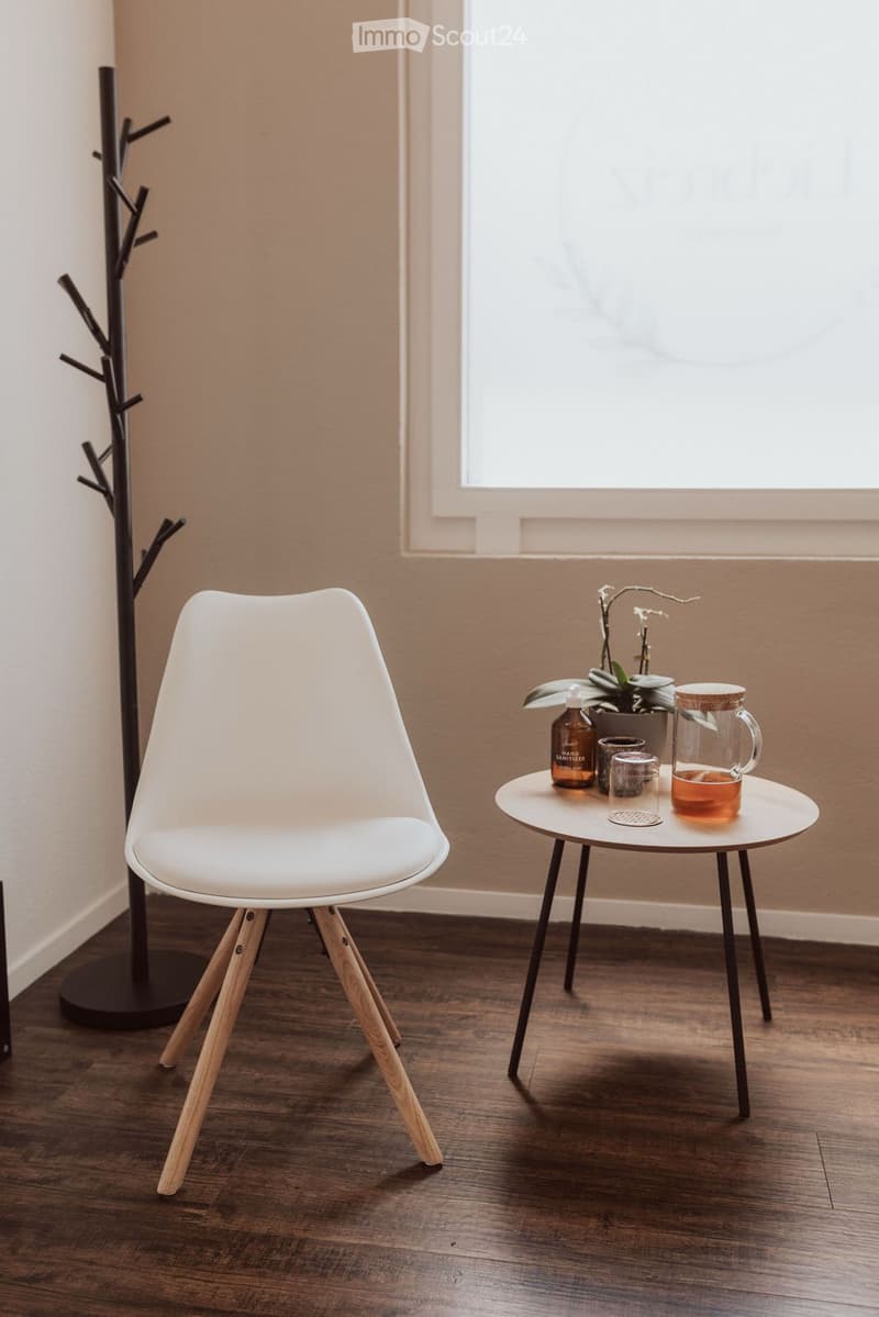 white chair, small round table, plant, window, wooden floor
