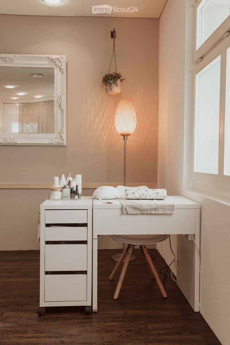 A room with a white desk, a chair, a lamp, a mirror, and a potted plant