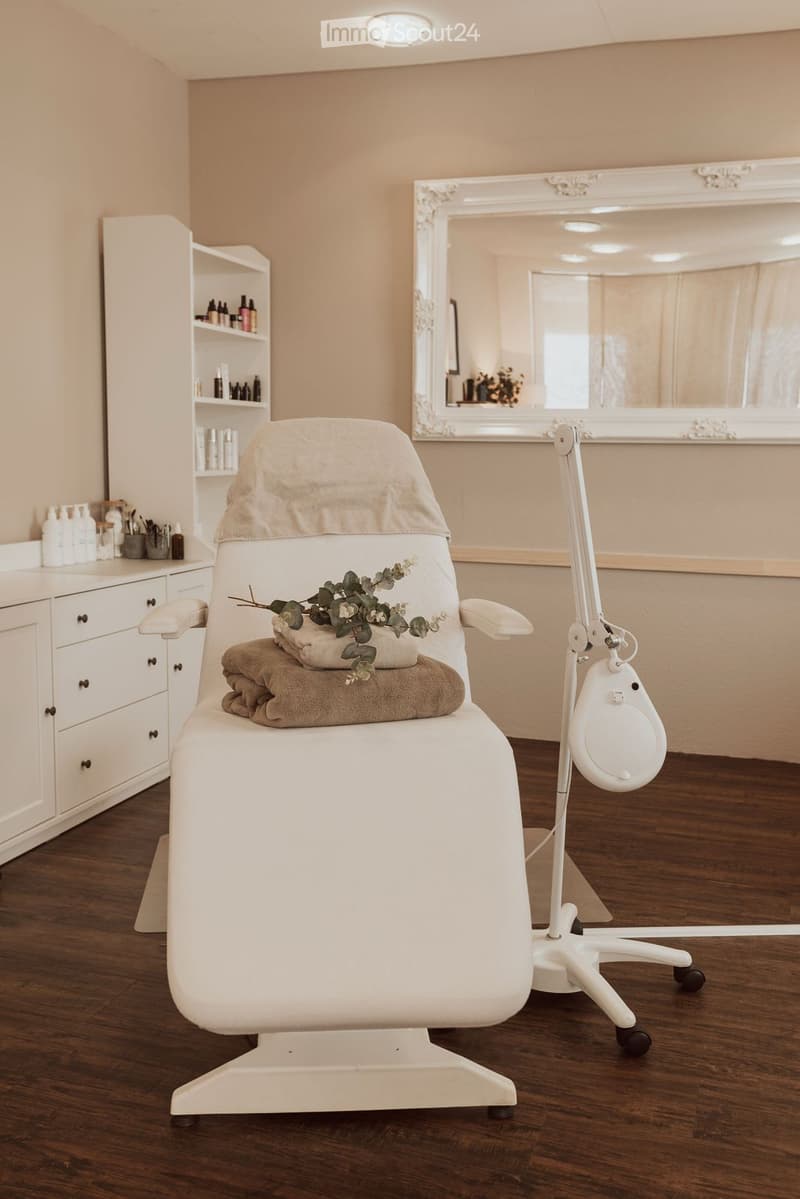 white massage chair, white cabinet, white shelves, white mirror, white desk, white towels, white lamp