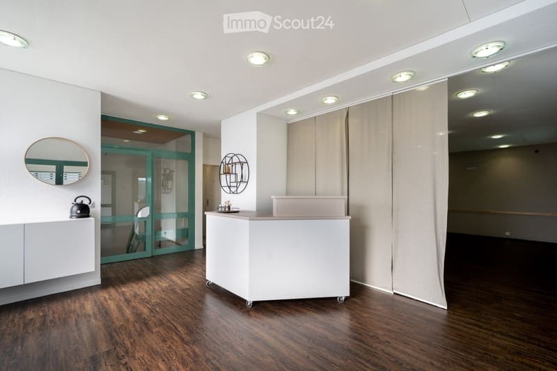 modern interior, white walls, wooden floor, white reception desk, round mirror, green glass door, ceiling lights