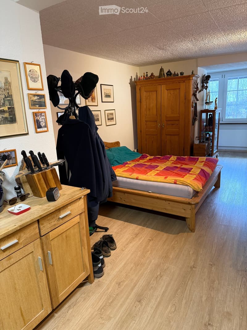 Bedroom with bed, wooden cabinet, wooden floor, wooden drawers, knife block, coat rack, framed pictures, wooden wardrobe, window, radiator