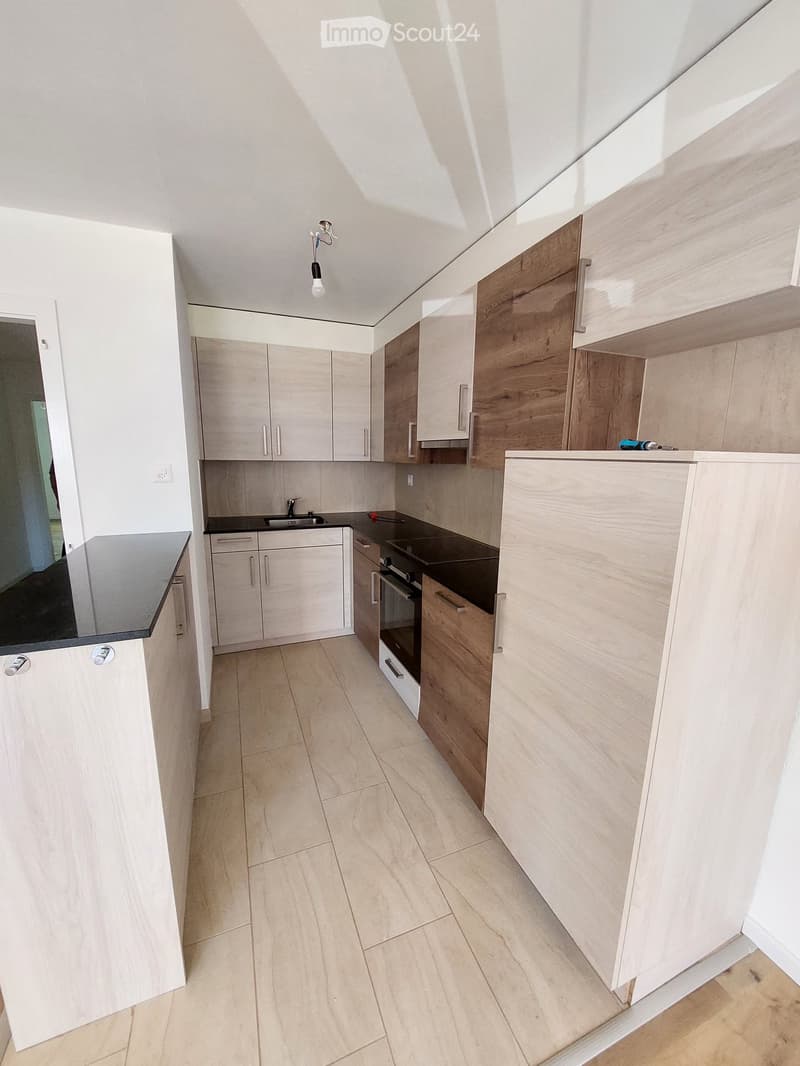 modern kitchen with wooden cabinets, black countertops, stainless steel appliances, tiled floor