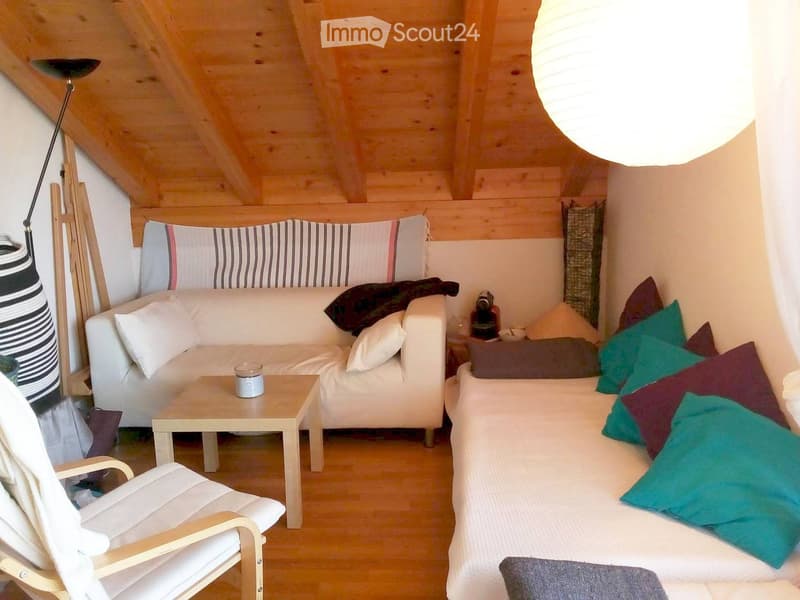 Cozy living room with wooden beams, white sofa, coffee table, and colorful cushions.