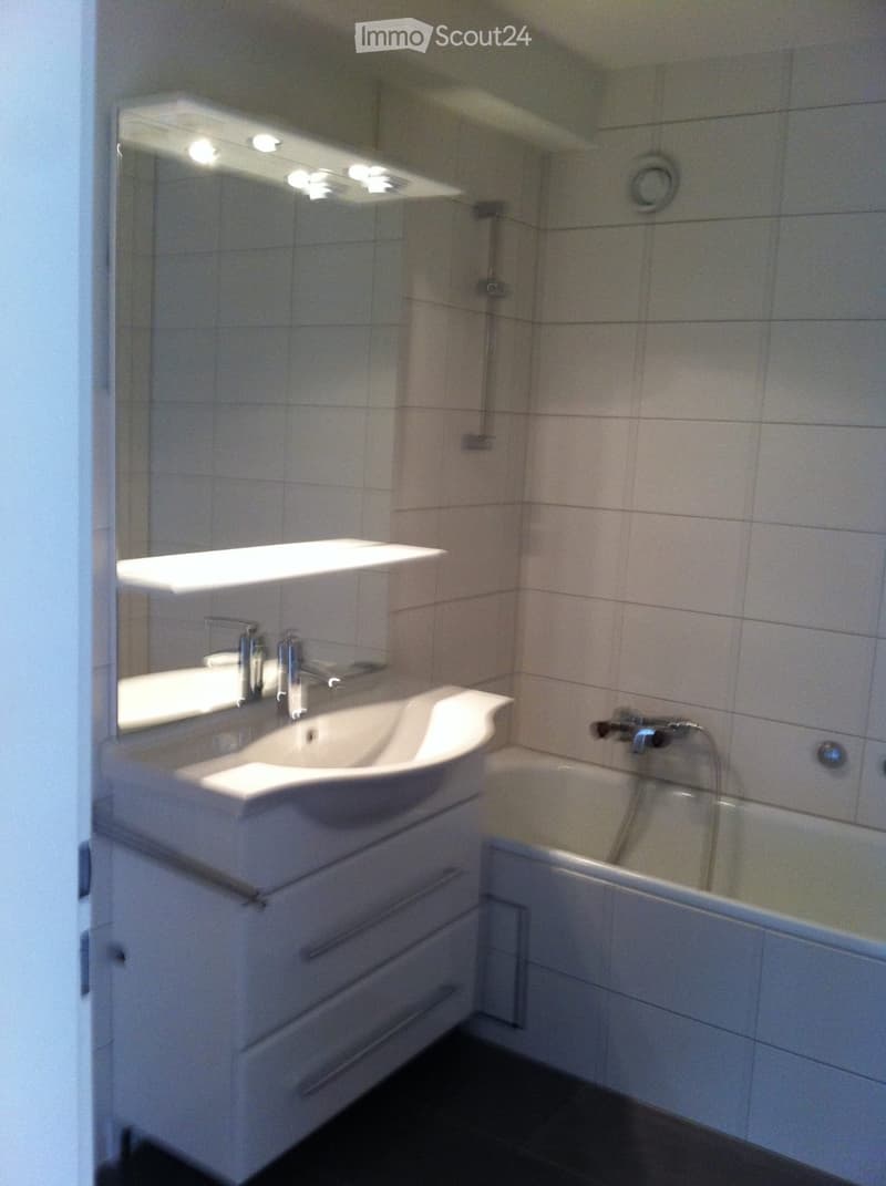Bathroom with white tiles, white sink, bathtub, mirror, and shower