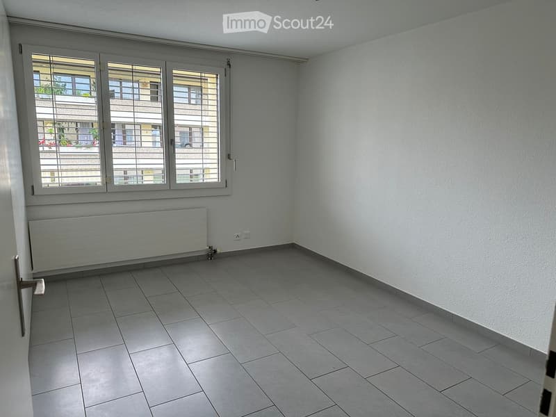 empty room, white walls, gray tiles, window with blinds, radiator, power outlets