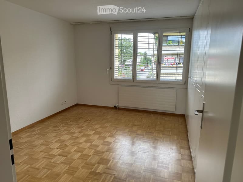 empty room, wooden floor, white walls, window with shutters, radiator, power outlets