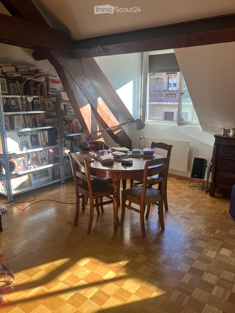 Wooden floor, wooden table and chairs, bookshelves, lamp, books, speaker, radiator, window