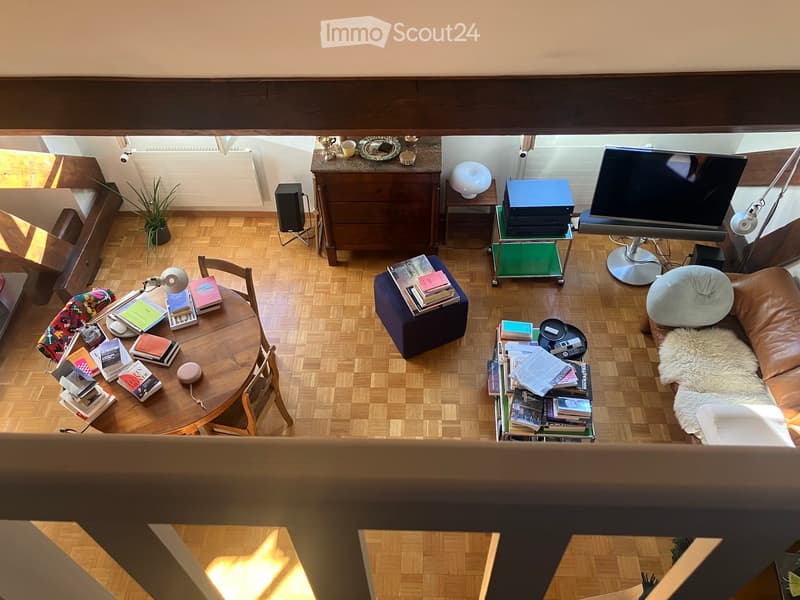 wooden floor, round table, chairs, ottoman, couch, books, TV, speaker, radiator, plant