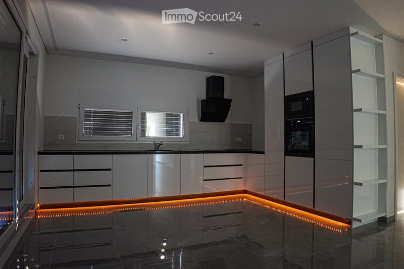 modern kitchen, white cabinets, black countertops, built-in oven and microwave, sink with faucet, LED strip lighting