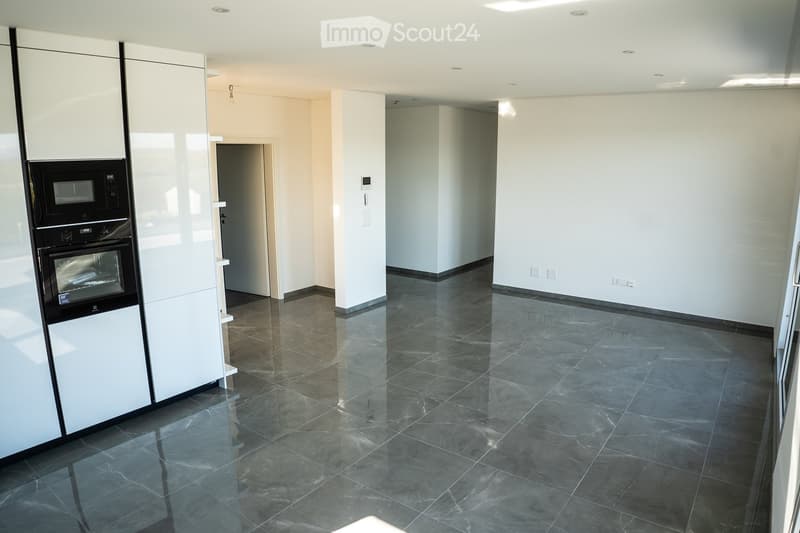 Empty room, white walls, gray tiles, built-in oven and microwave, open door