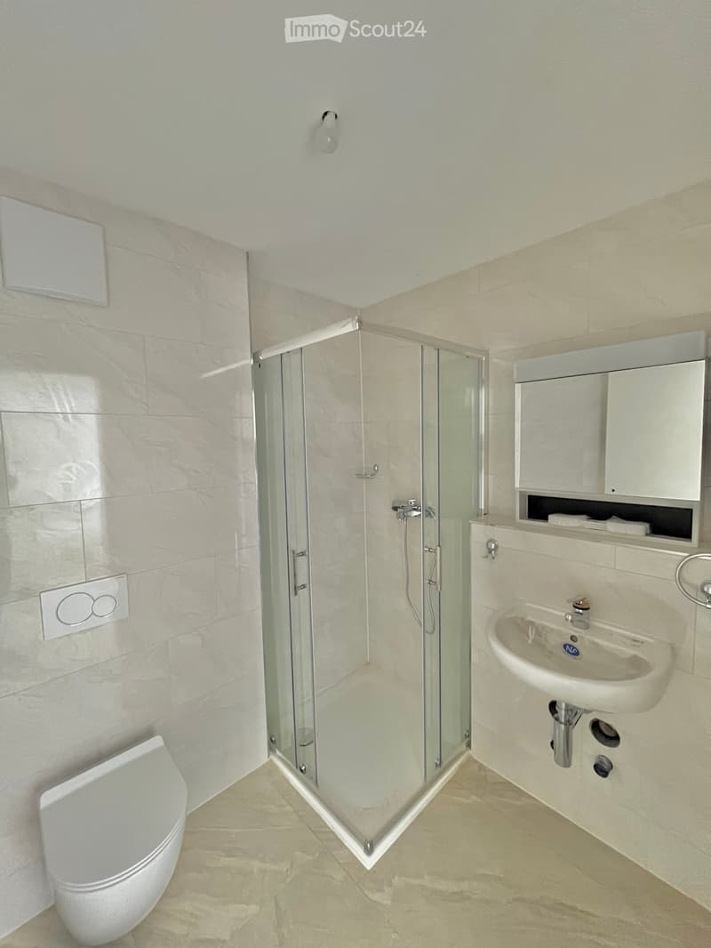 Bathroom with white tiles, glass shower enclosure, white sink, white toilet, white cabinet, white ceiling, white floor
