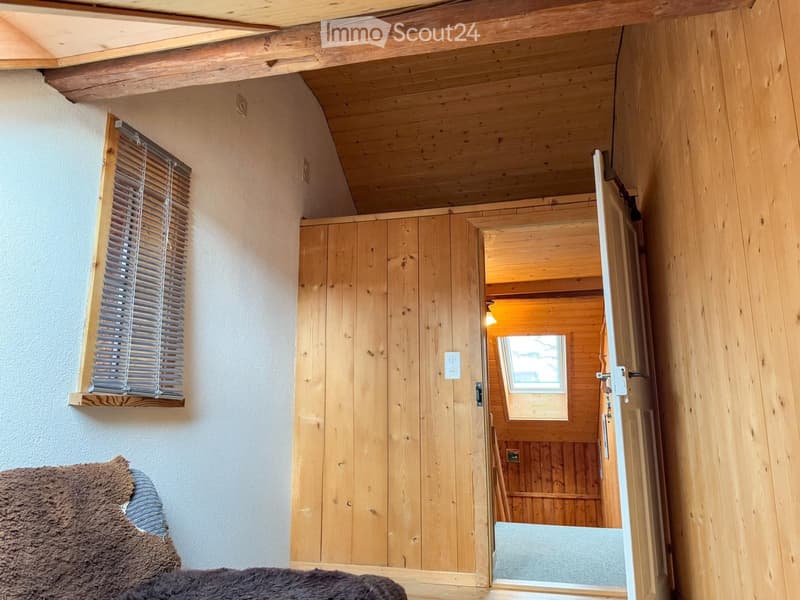 wooden walls, wooden ceiling, window with blinds, open door, carpeted floor, couch with blanket