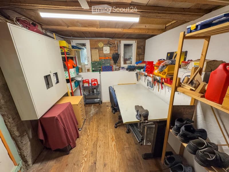 wooden floor, white walls, workbench, shelves, tools, storage boxes, clock, covered table, cabinet, shoes