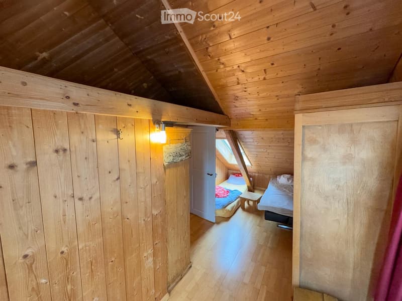 wooden walls, wooden floor, two beds, small table, light fixture, window