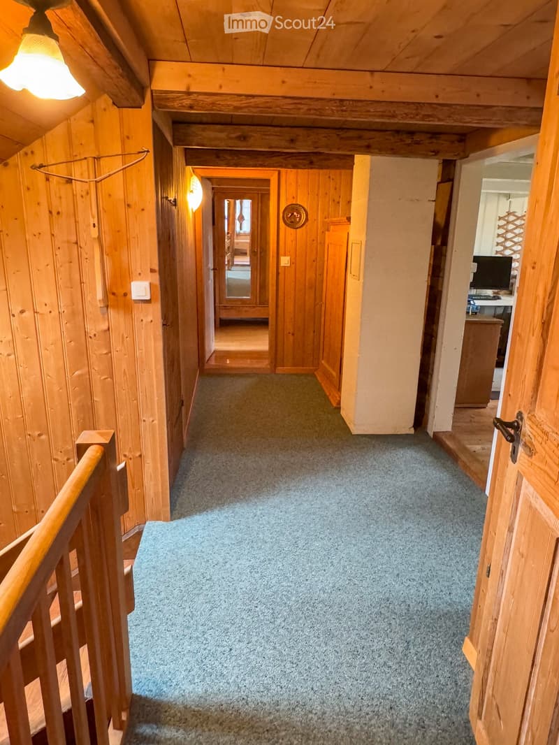 wooden walls, carpeted floor, wooden handrail, wooden door, light fixture