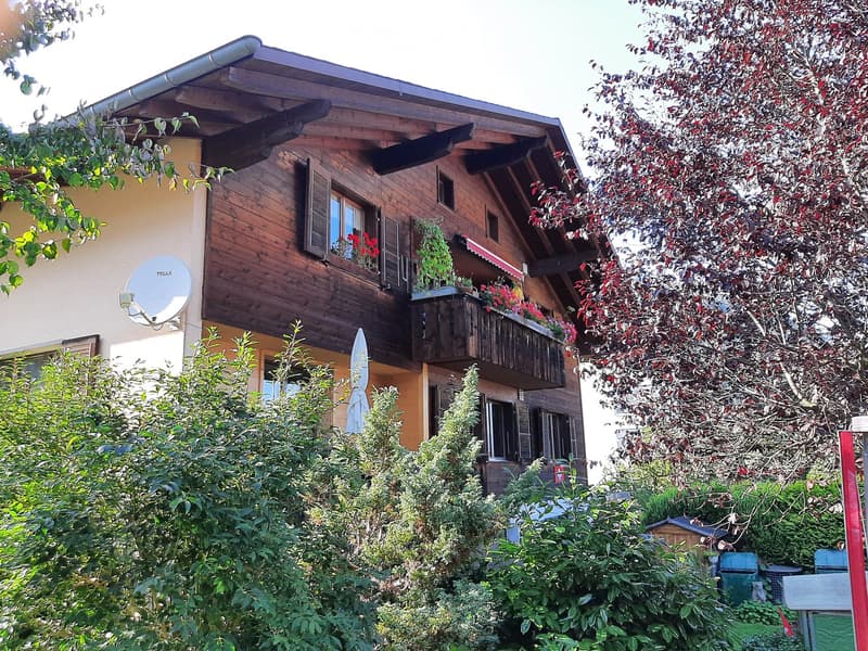 2 story wooden house, red flowers on balcony, satellite dish, red awning