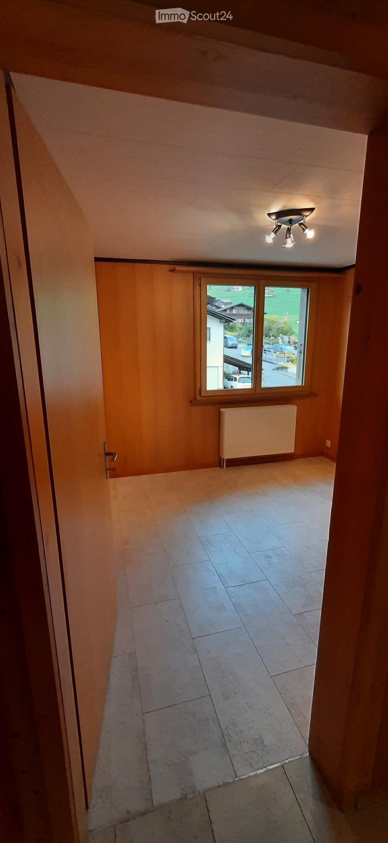 Empty room with wooden walls, tiled floor, window with view, radiator