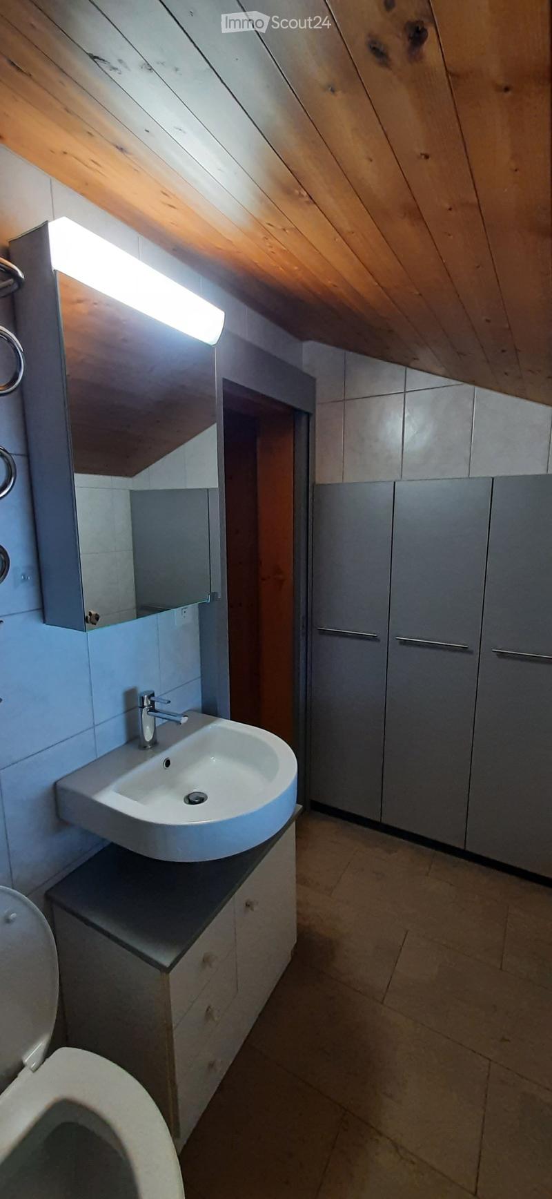 Bathroom with wooden ceiling, white sink, mirror, toilet, cabinets, tiled floor