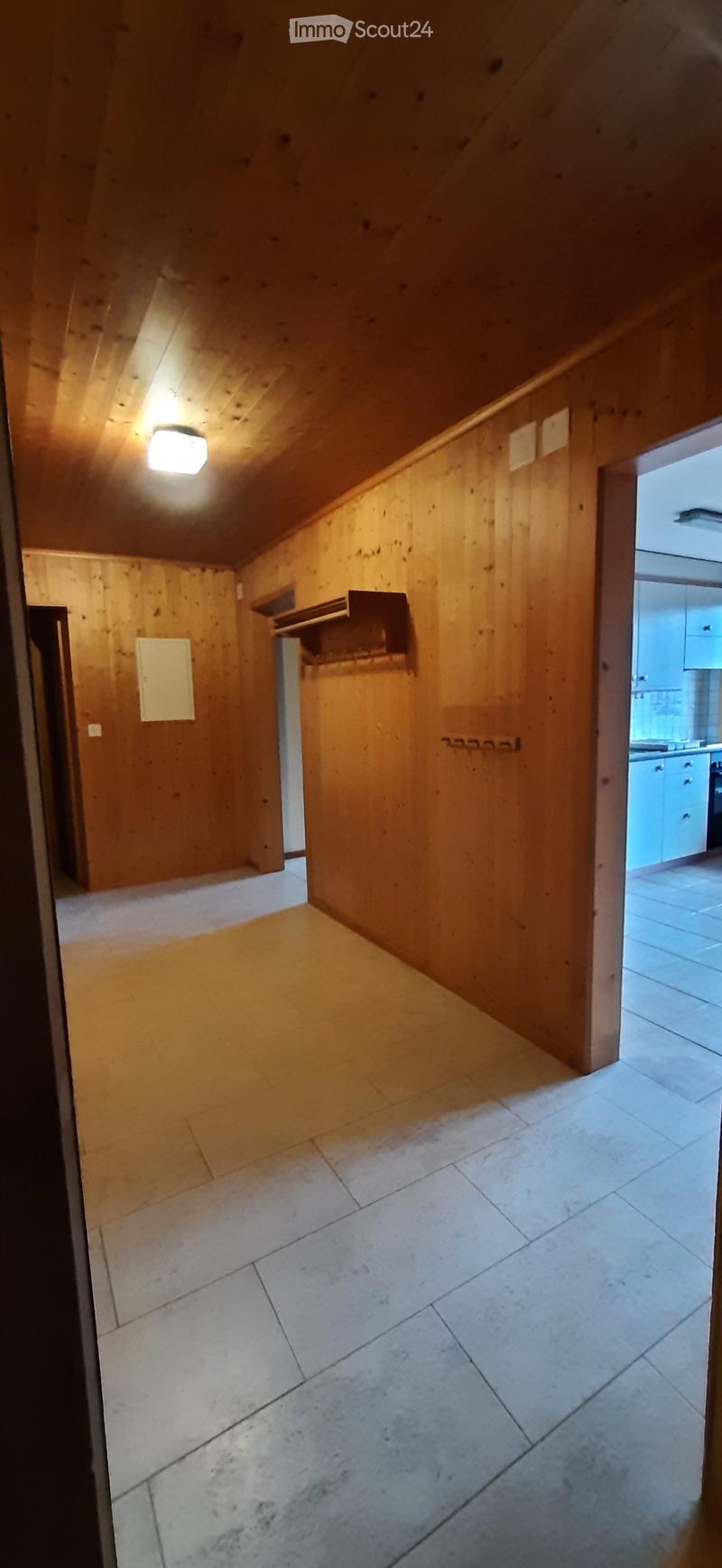 empty room, wooden walls, tiled floor, ceiling light, open door to another room