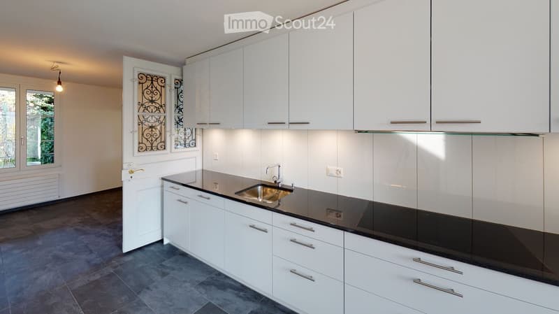 modern kitchen with white cabinets, black countertops, stainless steel sink, faucet, electrical outlets, and a window with decorative glass