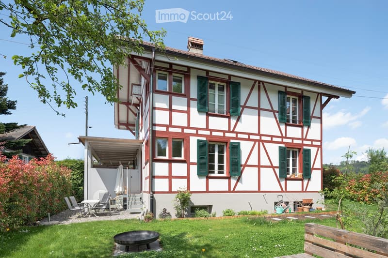 2 story house, red and white exterior, green shutters, covered patio, garden, outdoor seating