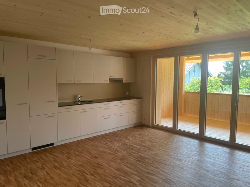 Kitchen. Modern kitchen with white cabinets, wooden flooring, and large sliding glass doors leading to a wooden deck.