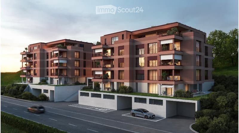 Multi-story apartment building with red brick exterior, balconies, and parking spaces in the front.