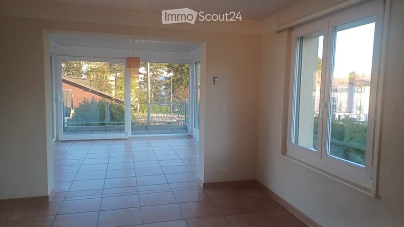 empty room, sliding glass doors, balcony, tiled floor, large windows, view of trees and buildings