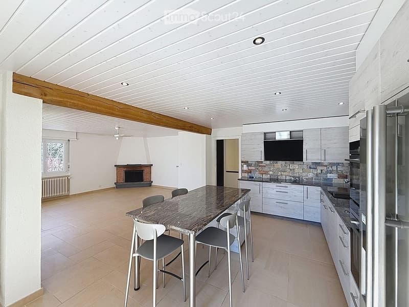 Open kitchen with dining area, fireplace, modern appliances, tiled floor, wooden beam