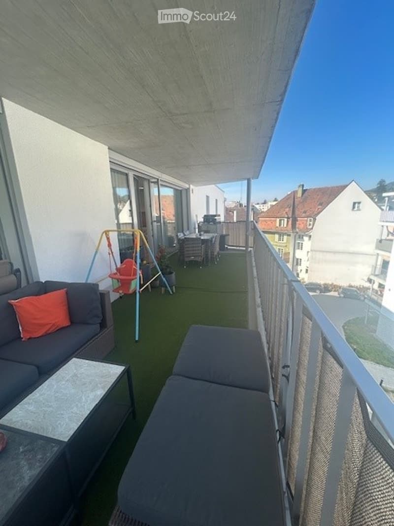 Outdoor balcony with a swing, a couch, and a coffee table.