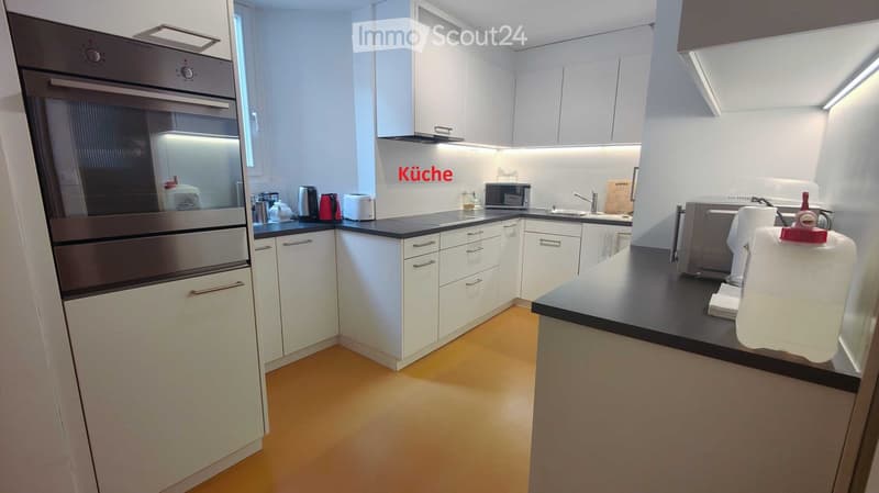 Modern kitchen with white cabinets, black countertops, and stainless steel appliances.