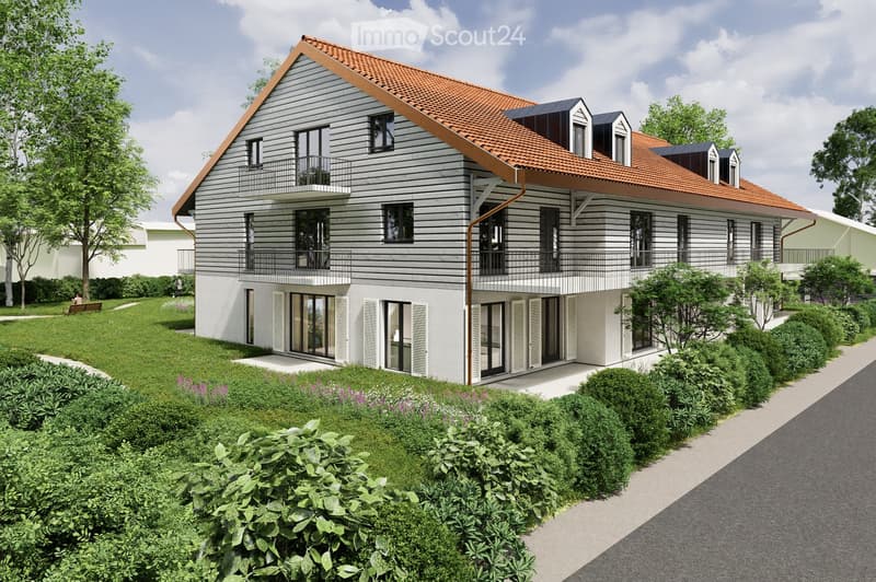 Modern two-story house with a red roof, white walls, and multiple windows. The house has a balcony on the second floor and is surrounded by greenery.