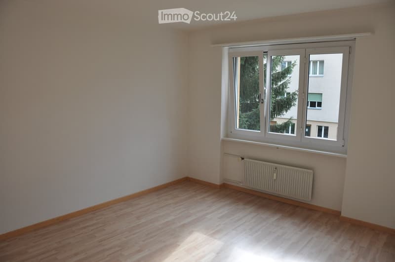 Unfurnished Room. Empty room with wooden flooring, white walls, and a large window with white frames. A radiator is visible below the window.