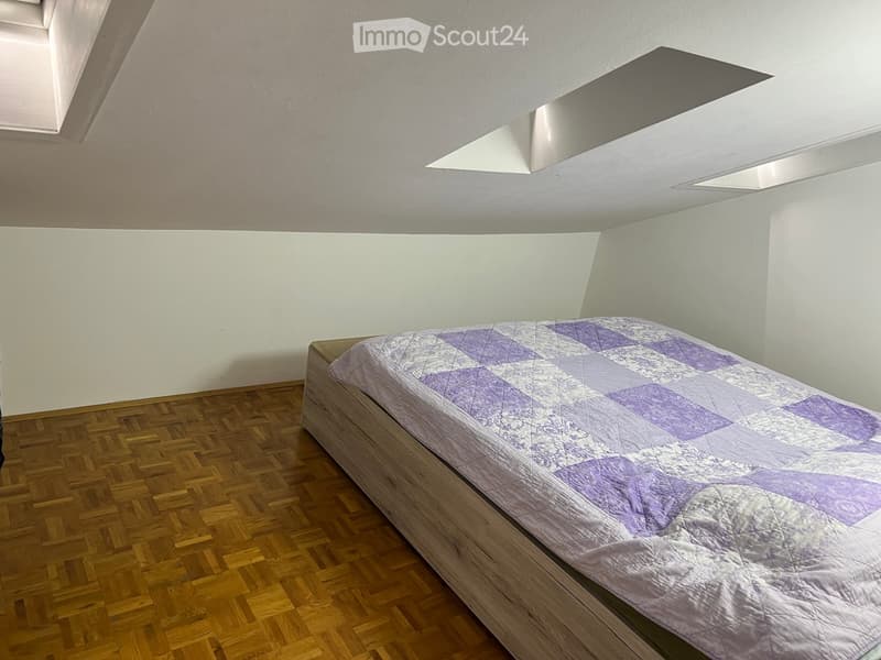 Bedroom. Minimalist bedroom with a single bed, wooden flooring, and white walls. The bed has a purple and white quilted cover.