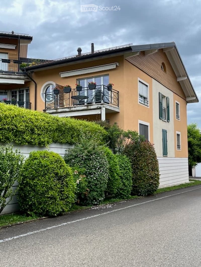 2 story house, beige and white, balcony, green bushes, road