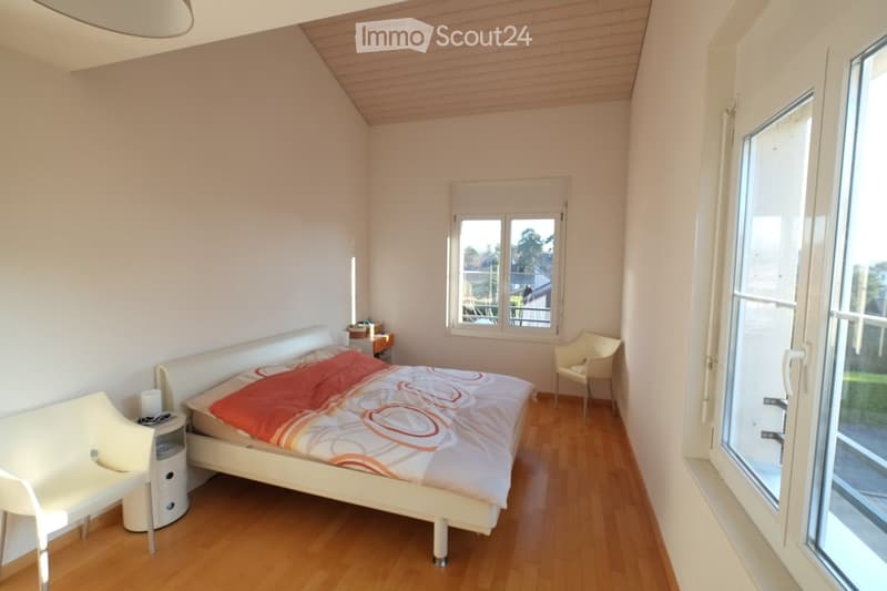 Bedroom with bed, bedside tables, chair, and windows