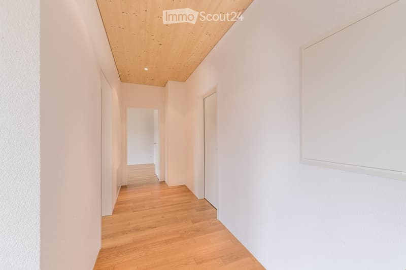 Empty hallway with wooden floor and white walls, wooden ceiling, doors on both sides