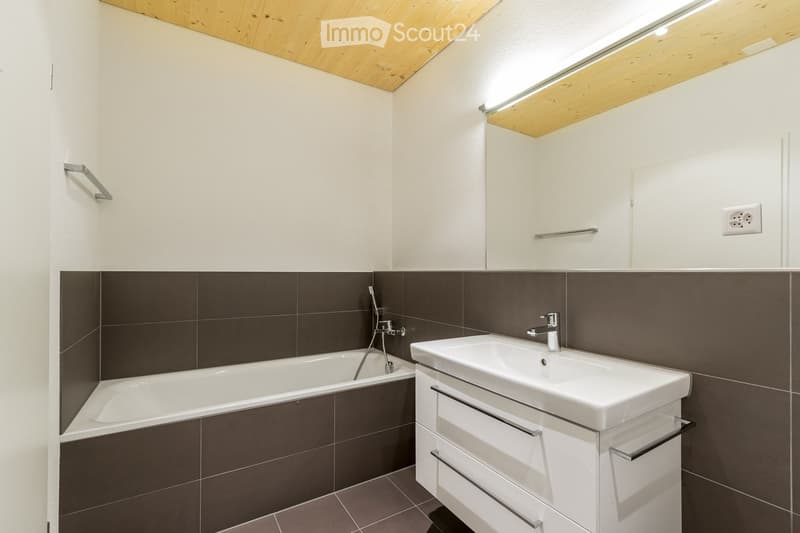 Bathroom with bathtub, sink, and mirror, tiled walls and floor, wooden ceiling
