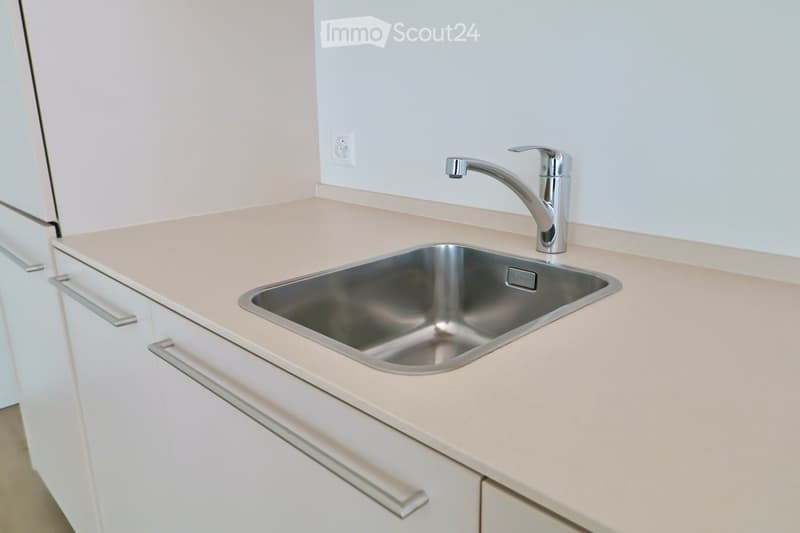 Modern kitchen with a stainless steel sink, silver faucet, and white cabinets.