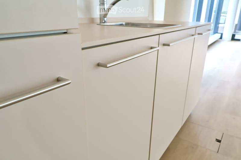Modern kitchen with white cabinets, stainless steel handles, and a stainless steel sink with a faucet.