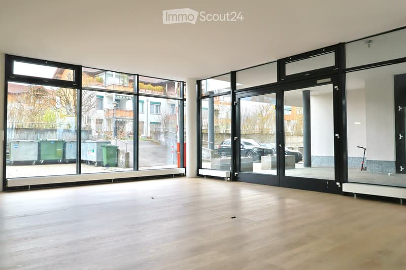Empty room with large windows, wooden floor, and modern glass doors. No furniture or equipment.