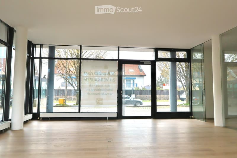 Empty room with large windows, wooden floor, and glass doors. No furniture or equipment.