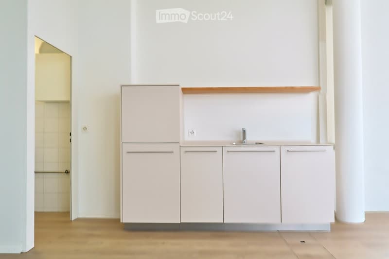 Modern kitchen with white cabinets, wooden countertop, and stainless steel sink.
