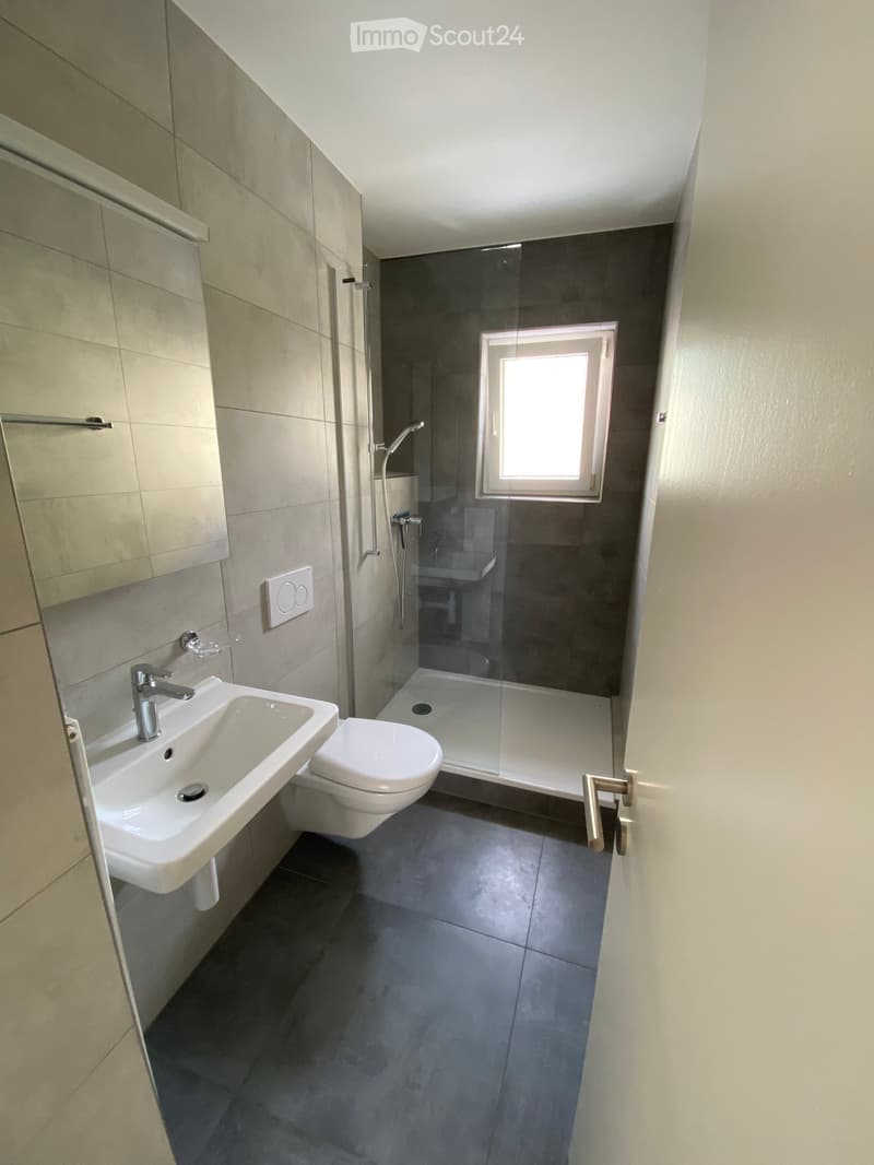 Bathroom with shower stall, sink, toilet, and window.