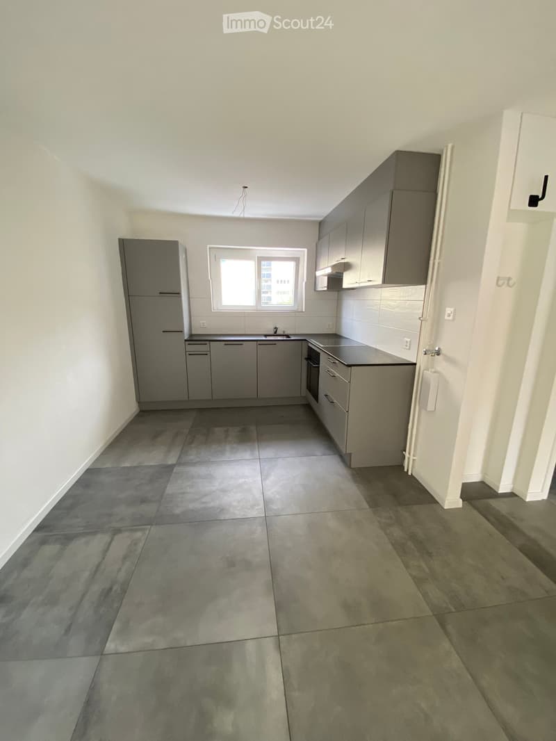 empty kitchen with tiled floor, gray cabinets, modern sink, and a window