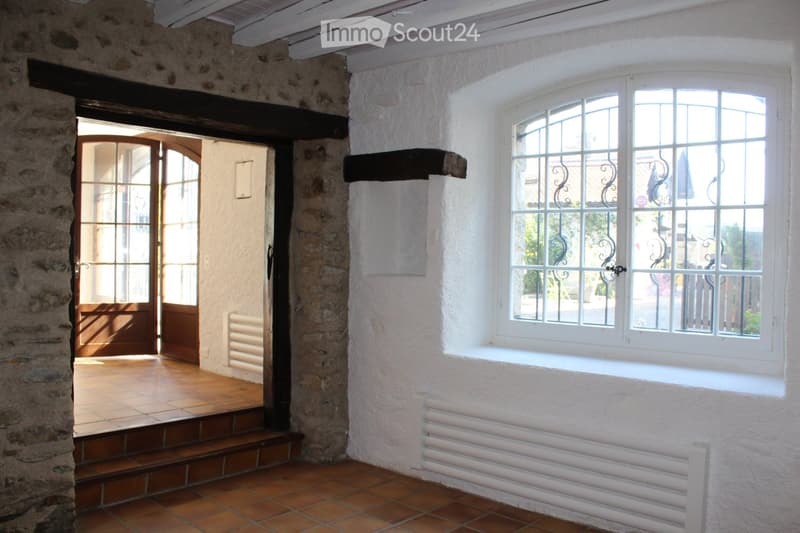 Stone wall, wooden door, tiled floor, white wall, window with metal grills